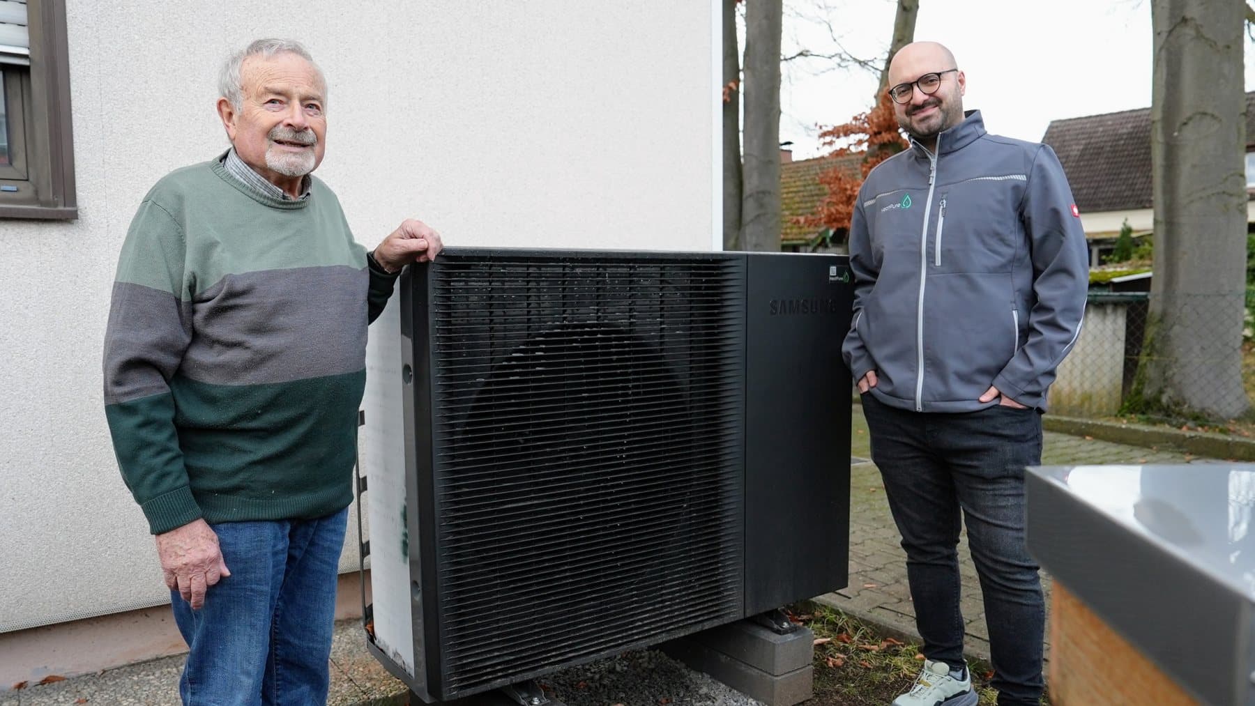 Kunde Karl und Durmus Pekel von HeatPure neben der Samsung-Wärmepumpe in Augsburg-Haunstetten
